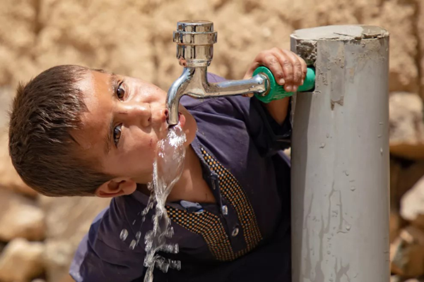 Child drinking water from faucet